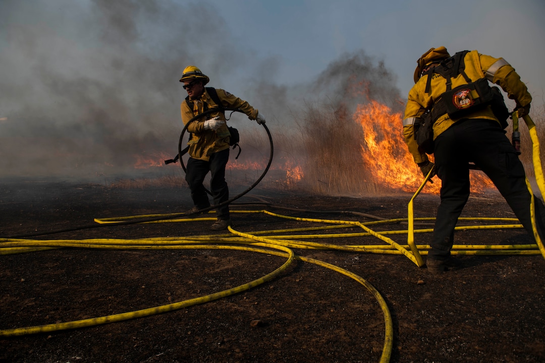 (Christian Monterrosa | AP)  Firefighters work to prevent flames from reaching nearby homes during the Easy Fire, Wednesday, Oct. 30, 2019, in Simi Valley, Calif. The fire has chewed through brush and trees near suburbs, horse ranches and the Ronald Reagan Presidential Library.