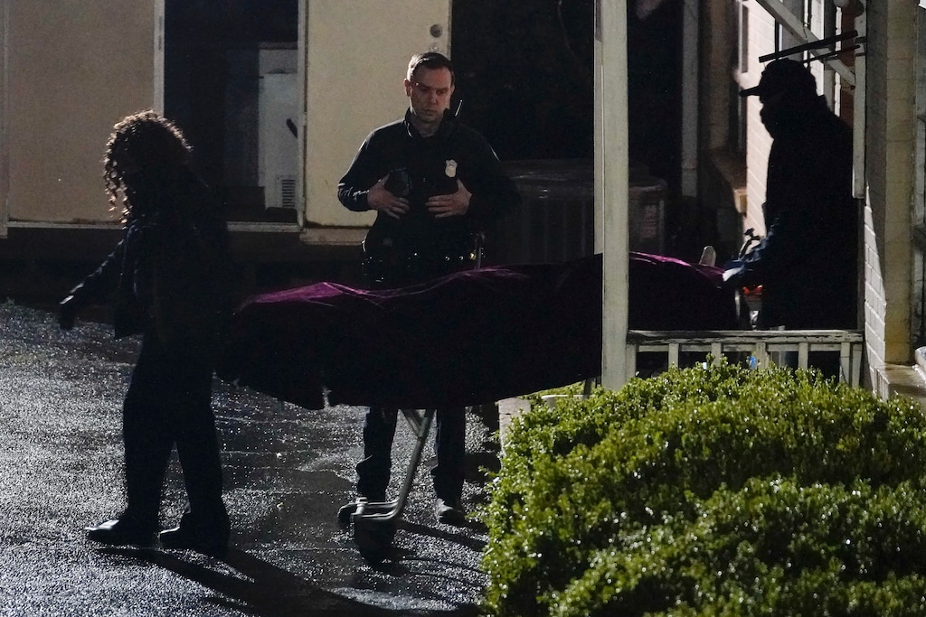 (Brynn Anderson | AP) A police officer watches as a body is taken from the Gold Spa massage parlor after a shooting, late Tuesday, March 16, 2021, in Atlanta. Shootings at two massage parlors in Atlanta and one in the suburbs left multiple people dead, many of them women of Asian descent, authorities said. A 21-year-old man suspected in the shootings was taken into custody in southwest Georgia hours later after a manhunt, police said.