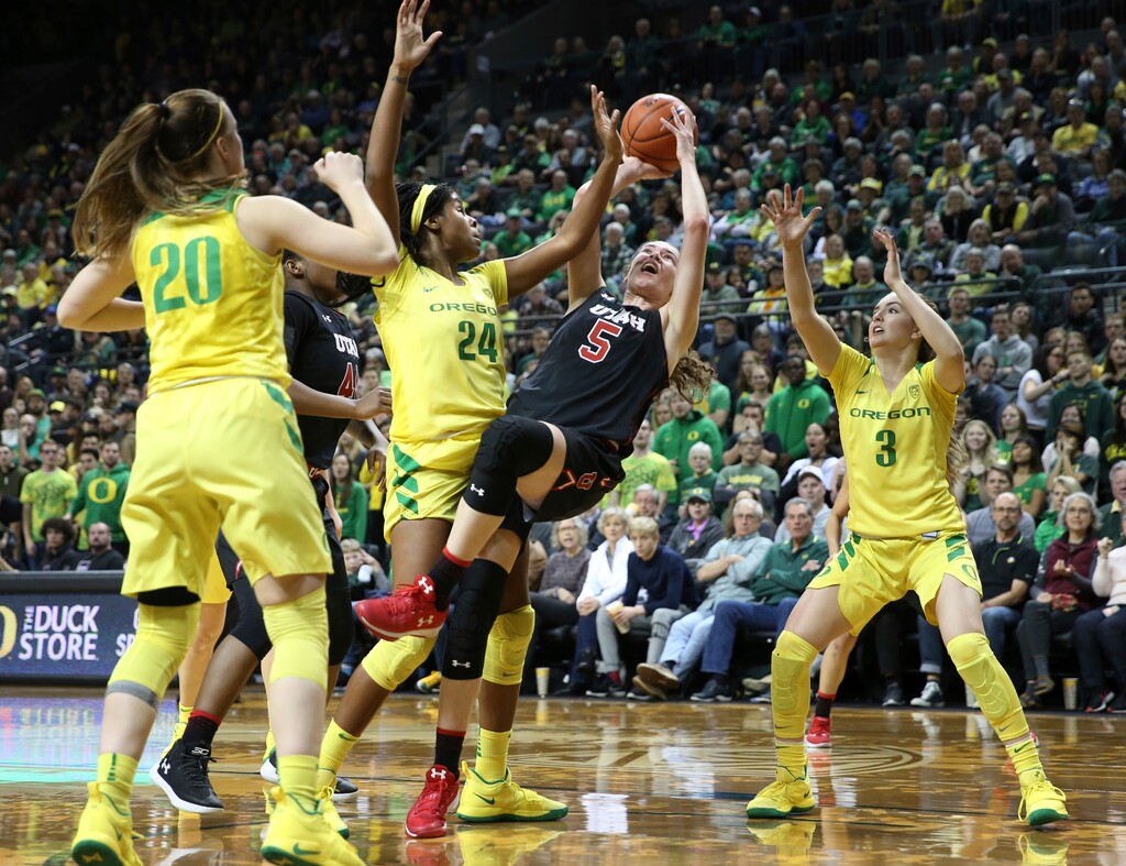 Utah's Megan Huff, enter, shots as she falls under pressure from Oregon's Sabrina Ionescu, left, Ruthy Hebard and Taylor Chavez, right, during the third quarter of an NCAA college basketball game Friday, Feb. 1, 2019, in Eugene, Ore. (AP Photo/Chris Pietsch)