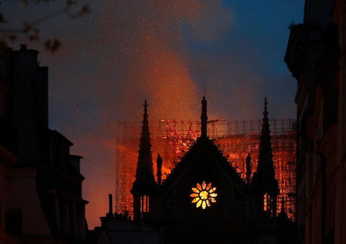 Flames and smoke rise from Notre Dame cathedral as it burns in Paris, Monday, April 15, 2019. Massive plumes of yellow brown smoke is filling the air above Notre Dame Cathedral and ash is falling on tourists and others around the island that marks the center of Paris. (AP Photo/Thibault Camus)