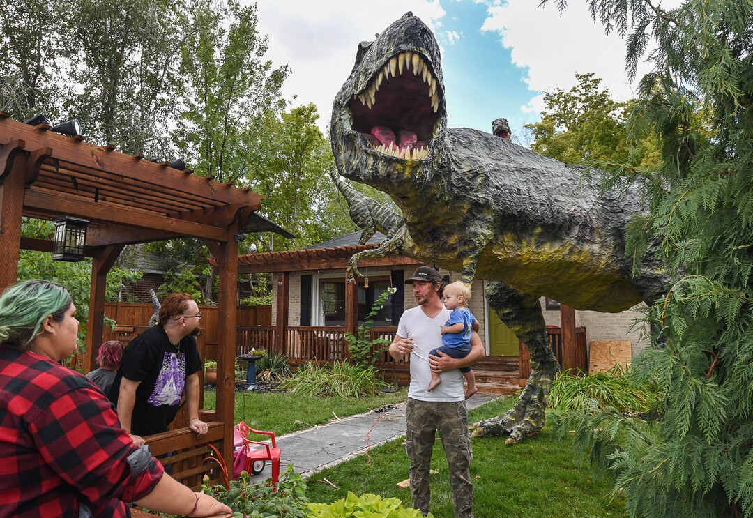 (Francisco Kjolseth  |  The Salt Lake Tribune)  Ammon Smith talks about the process as fans stop by to chat about his latest Halloween creation at 1542 S. 900 East in Salt Lake City for Halloween after constructing a "maturing adult"-size T. rex along with a pair of velociraptors and pterodactyls. The part-time stay-at-home dad, who made a giant King Kong last year, started construction back in August as he assembled recycled wood, chicken wire, foam, aluminum foil and spray paint for the 12-by-32-foot Jurassic centerpiece and companion pieces.