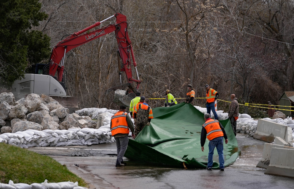 (Francisco Kjolseth | The Salt Lake Tribune) Crews temporarily stop water flow as they lay down material to reduce erosion across 1700 South in Salt Lake during efforts to clear storm drains and safely channel runoff from Emigration Creek through Wasatch Hollow Park on Friday, April 14, 2023.