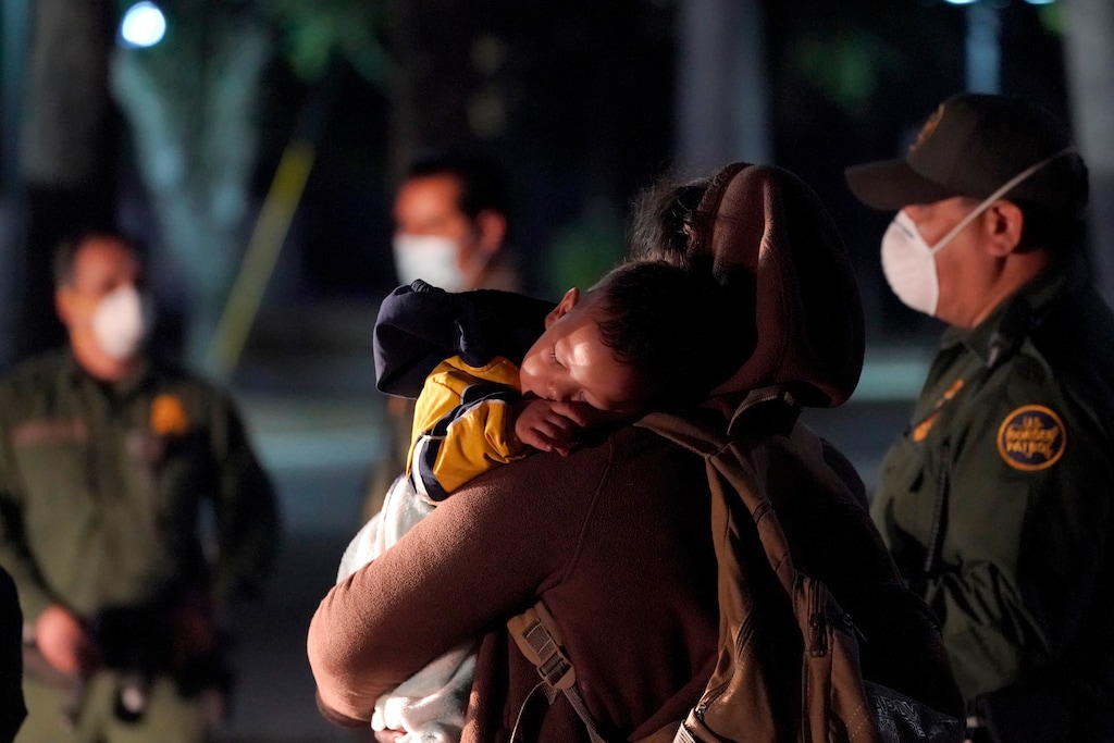 (Julio Cortez | AP) A migrant child sleeps on the shoulder of a woman at an intake area after turning themselves in upon crossing the U.S.-Mexico border, early Wednesday, March 24, 2021, in Roma, Texas.