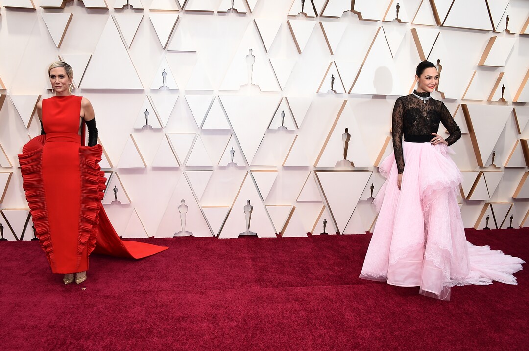 (Jordan Strauss | Invision/AP)  Kristen Wiig, left, and Gal Gadot arrive at the Oscars on Sunday, Feb. 9, 2020, at the Dolby Theatre in Los Angeles