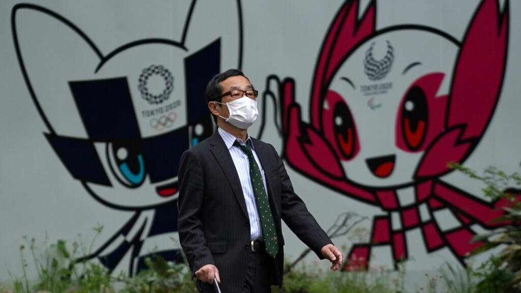 A man with a face mask against the spread of the new coronavirus walks in front of Miraitowa and Someity, mascots for the Tokyo 2020 Olympics and Paralympics at a park in Tokyo Tuesday, April 28, 2020. Japan's Prime Minister Shinzo Abe expanded a state of emergency to all of Japan from just Tokyo and other urban areas as the virus continues to spread. (AP Photo/Eugene Hoshiko)