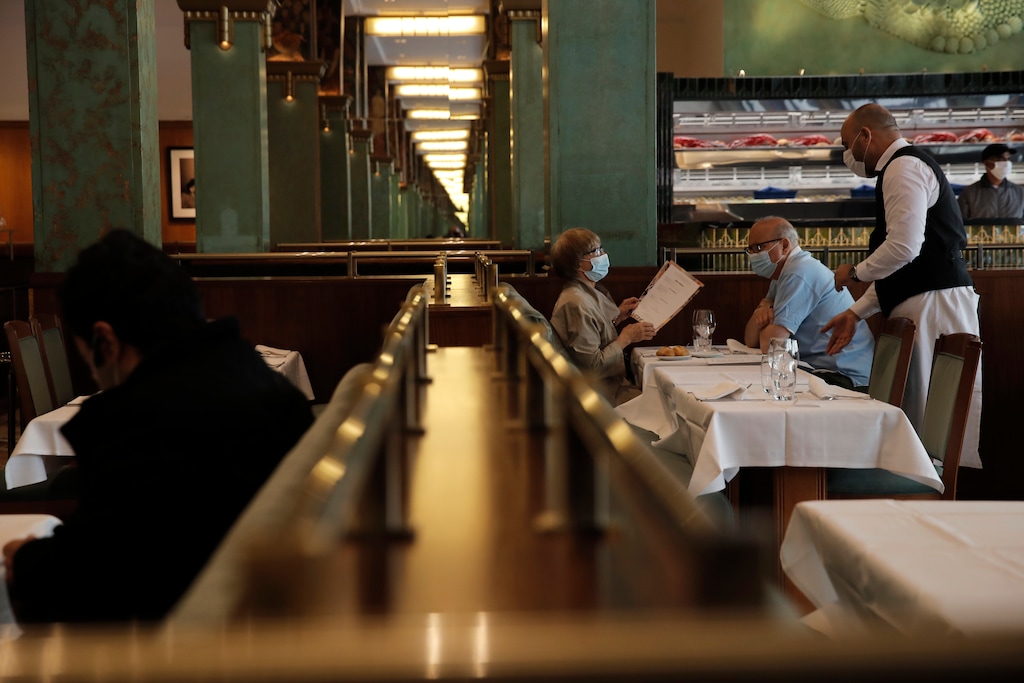 (Christophe Ena | AP) A waiter answers a client at La Coupole restaurant, Monday, June 15, 2020 in Paris. Paris is rediscovering itself, as its cafes and restaurants reopen for the first time since the fast-spreading virus forced them to close their doors March 14. Restaurants outside the Paris region opened earlier this month, and Paris cafes were allowed to serve people outside but not open their doors. After three months of losses, some restaurateurs fear it will take a long time for business to come back.