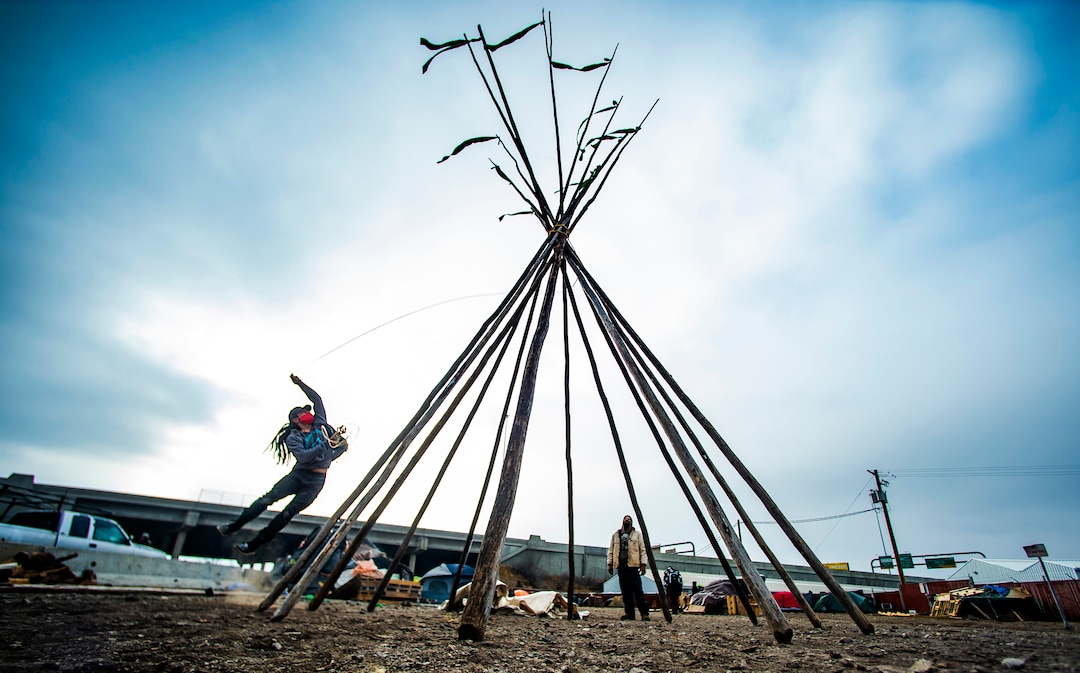 (Rick Egan | The Salt Lake Tribune) Carl Moore jumps to tighten the ropes as he erects a teepee at Camp Last Hope, to help shelter people experiencing homelessness that lost their tents when they were forced to move, on Thursday, Dec. 31, 2020.