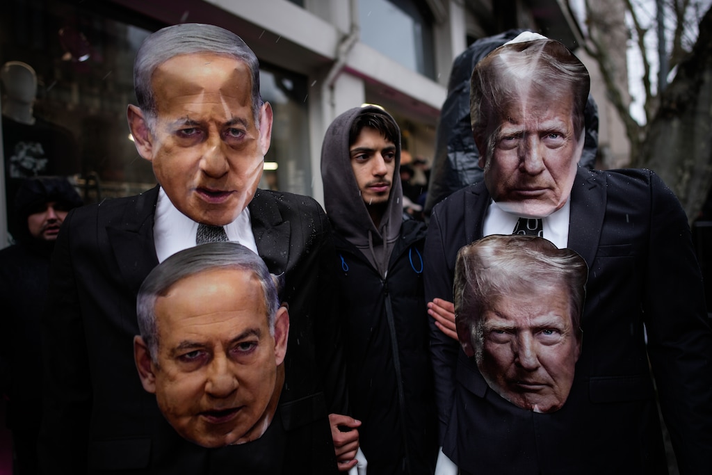 A man holds two mannequins depicting U.S. President Donald Trump and Israel's Prime Minister Benjamin Netanyahu during a rally in support of the Iranian government, in Istanbul, Turkey, Sunday, Jan. 18, 2026. (AP Photo/Emrah Gurel)
