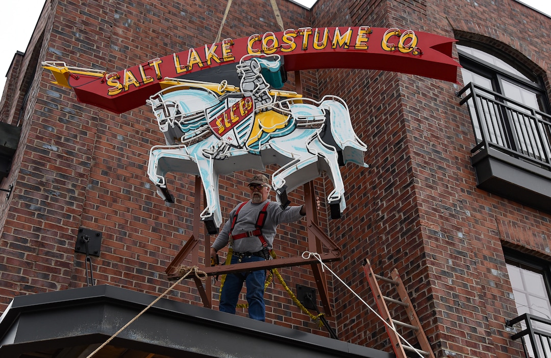(Francisco Kjolseth  |  The Salt Lake Tribune)  Cory Barker of Rainbow Neon Sign Co. maneuvers the Salt Lake Costume Co. sign, back home in its original location at 1700 S. 1100 East on Monday, Dec. 23, 2019, in what is now called the Salt Lake Costume Apartments.