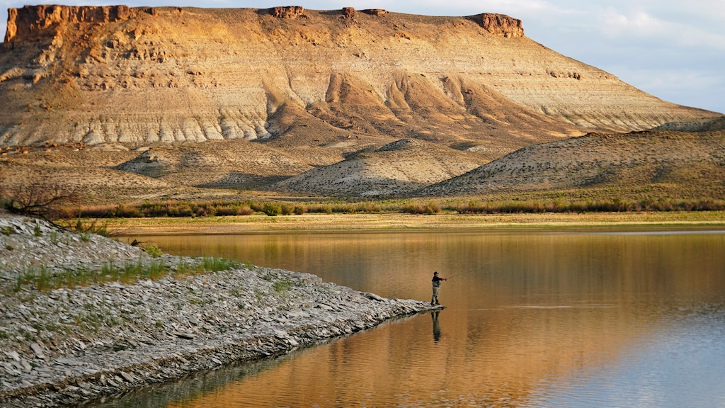 (Rick Bowmer | AP) Nick Gann fishes in Firehole Canyon Friday, Aug. 5, 2022, on the far northeastern shore of Flaming Gorge Reservoir, in Wyoming. A boating and fishing paradise on the Utah-Wyoming line, Flaming Gorge is beginning to feel the effects of the two-decade megadrought gripping the southwestern U.S.