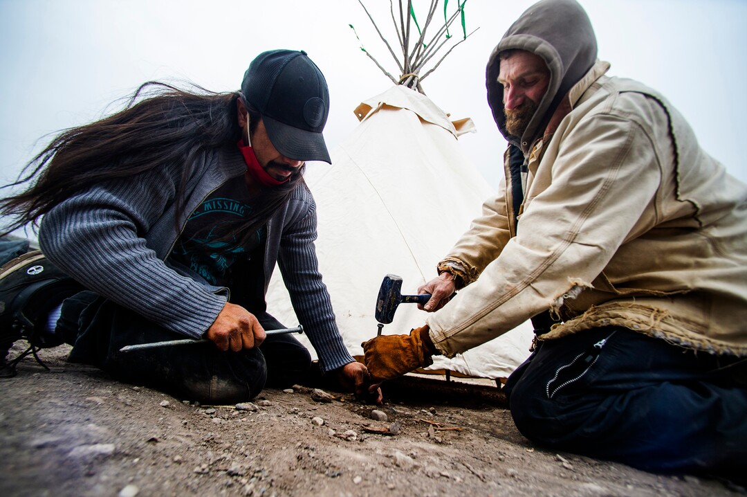 (Rick Egan | The Salt Lake Tribune) Carl Moore and Tony Pullam pound stakes in the ground for the teepee at Camp Last Hope, on Thursday, Dec. 31, 2020.