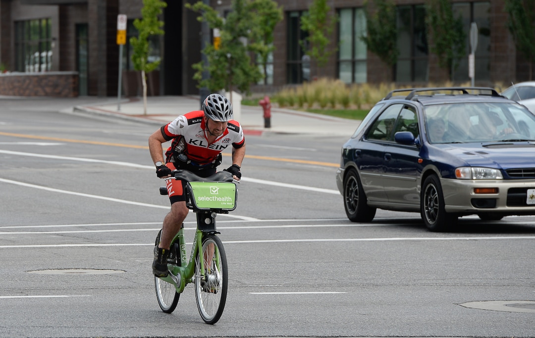 (Francisco Kjolseth  |  The Salt Lake Tribune)  Salt Lake Tribune reporter Ben Wood nears the finish line on his Green Bike during a race against colleagues with different forms of downtown transportation from Library Square to the Tribune building at the Gateway on Thursday, Aug. 2, 2018. Modes of transportation included, rentable electric scooters, Green Bike, TRAX, Lyft, and walking.