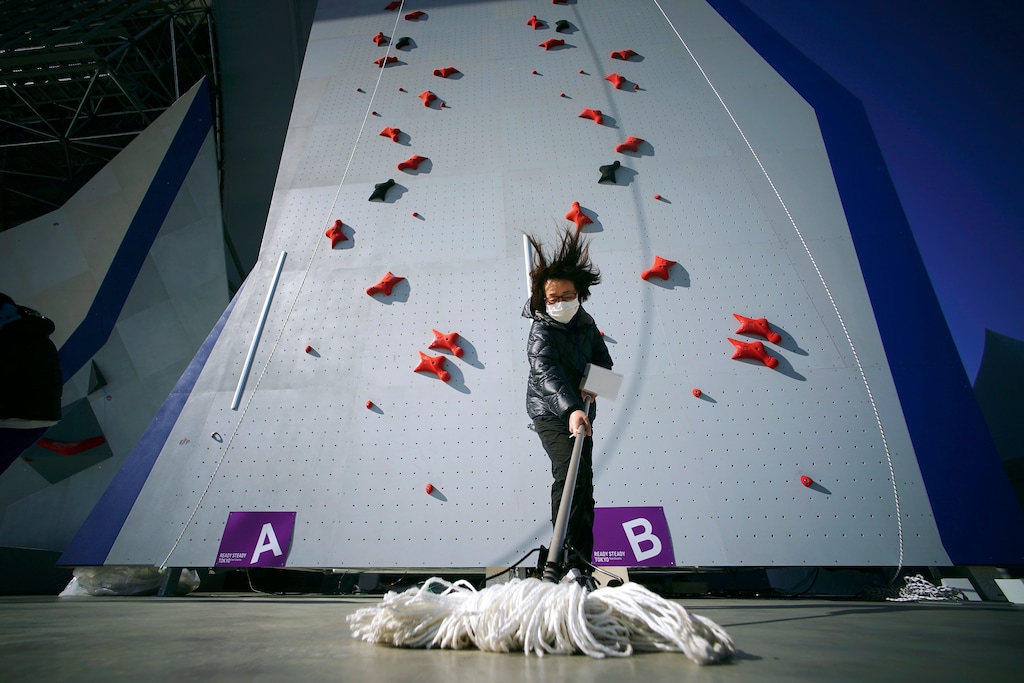 (Eugene Hoshiko | AP) A Tokyo 2020 Olympic Games Organizing staff mops the floor in front of the climbing wall in the test event of Speed Climbing in preparation for the Tokyo 2020 Olympic Games at Aomi Urban Sports Park in Tokyo, March 6, 2020. The tentacles of canceling the Tokyo Olympics — or postponing or staging it in empty venues — would reach into every corner of the globe, much like the spreading virus that now imperils the opening ceremony on July 24.