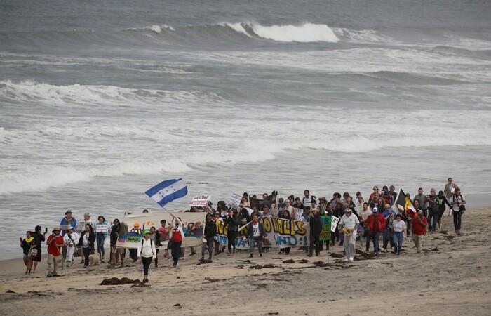 Demonstrators march to meet Central American migrants traveling in a caravan for a gathering at the border on the beach where the border wall ends in the ocean, Sunday, April 29, 2018, in San Diego. (AP Photo/Chris Carlson)
