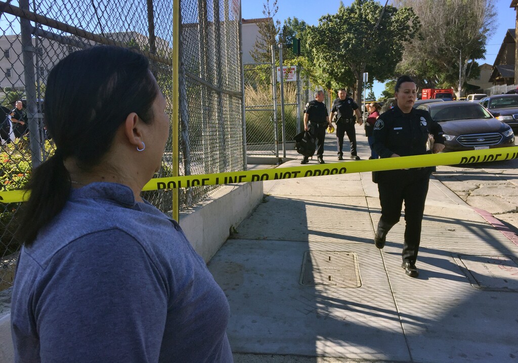 Gloria Echeverria watches as Los Angeles police officers close off a street where a shooting occurred at a middle school in Los Angeles on Thursday, Feb. 1, 2018. Two students were shot inside the middle school classroom Thursday morning and police arrested a female student suspect, authorities said. (AP Photo/Amanda Lee Myers)