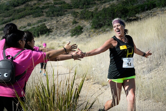 (Scott Sommerdorf | The Salt Lake Tribune) Runner Jane Ballard gets some high fives and encouragement from a family on the course. Ballard was racing toward the finish line near the Soldier Hollow train station, trying to beat the Heber Creeper train in a 12k race. The race started at the Deer Creek Dam, Saturday, August 19, 2017.