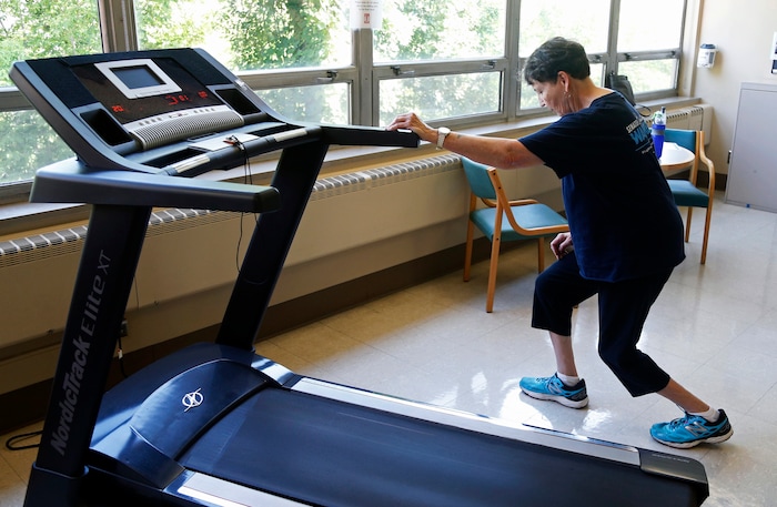 In this Aug. 15, 2017, photo, Rita Driscoll stretches before she walks on a treadmill at University of Minnesota Medical Center in Minneapolis. After years of leg pain slowing her down, Driscoll learned she has peripheral artery disease, or PAD. Medicare soon will start paying hospitals and clinics for these exercise sessions, making the therapy available for thousands of older Americans with a specific type of leg pain. (AP Photo/Jim Mone)