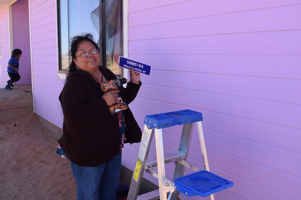 (Courtesy of Rural Utah Project) Dalene Redhorse, a field organizer for the Rural Utah Project, hangs a Plus Code sign on a Navajo Nation home south of Bluff, on Oct. 10, 2019.