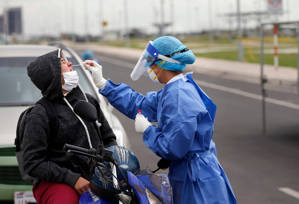 (Jorge Saenz | AP) A nurse from the Ministry of Public Health takes a sample from a person on a motorcycle, at a new coronavirus mobile test site in Asuncion, Paraguay, Wednesday, April 8, 2020. The government of Paraguay has announced the extension of the quarantine for one week until April 21.