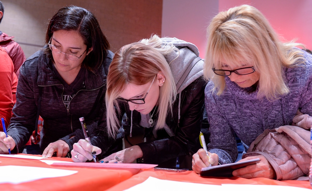 (Leah Hogsten | Tribune file photo) l-r Herriman residents Aubrey Cruz and Nicole Newby sign up to volunteer to help with an anti-Olympia Hills development referendum as Patricia Stanko writes out check to donate to the cause, Mar. 4, 2020. Herriman residents attended Utah for Responsible Growth news conference at Mountain Ridge High School to discuss the group's plan to block the project.