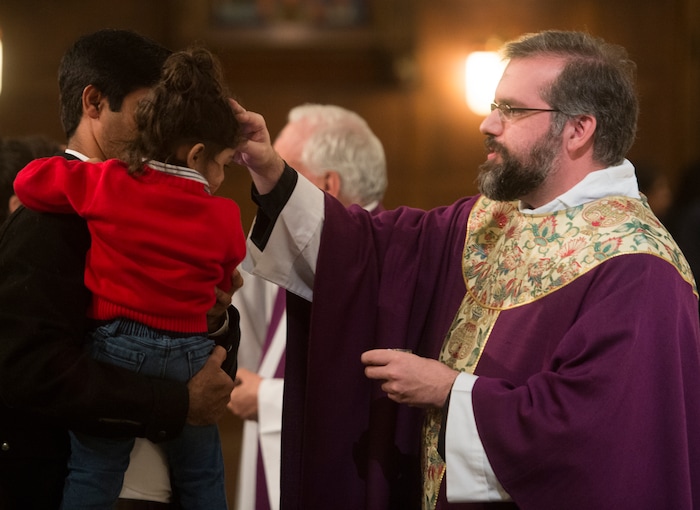 (Rick Egan | The Salt Lake Tribune) The Reverend Christopher P. Gray, dispenses ashes, on the forehead of a young girl, during the Ash Wednesday Mass, at the Cathedral of The Madeleine, Wednesday, Feb. 14, 2018.