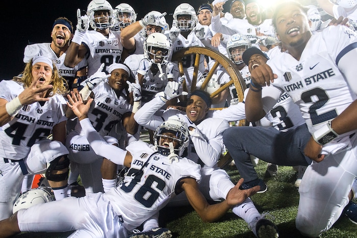(Chris Detrick  |  The Salt Lake Tribune)  Utah State Aggies pose for pictures with the Old Wagon Wheel after the game at Merlin Olsen Field at Maverik Stadium Friday, September 29, 2017. Utah State Aggies defeated Brigham Young Cougars 40-24.