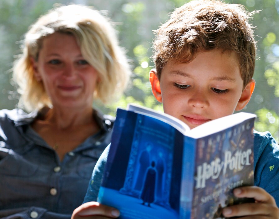 (Seth Wenig | AP File Photo)Theo Galkin, 8, rereads a favorite part of "Harry Potter and the Sorcerer's Stone" while posing for a picture with his mother Chloe Galkin at their New Jersey home in 2017.