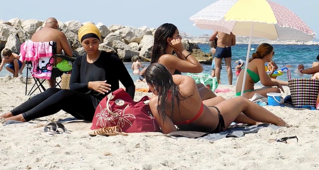 In this image taken from video, Nesrine Kenza who says she is happy to be free to wear a burkini, and two unidentified friends rest on the beach in Marseille, France, Monday Aug. 29, 2016. A high court struck down the previous ban of the wearing of so called burkini Friday, but the debate revealed raw tensions between the secular establishment and sectors of France's estimated 5 million Muslims. (AP Photo)