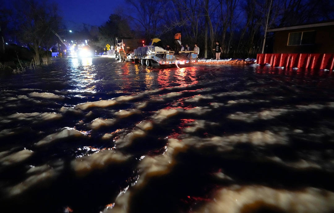 (Francisco Kjolseth | The Salt Lake Tribune) People work to protect homes into the night along 1700 South in Salt Lake City from the rising flow of Emigration Creek through Wasatch Hollow Park on Wednesday, April 12, 2023. 