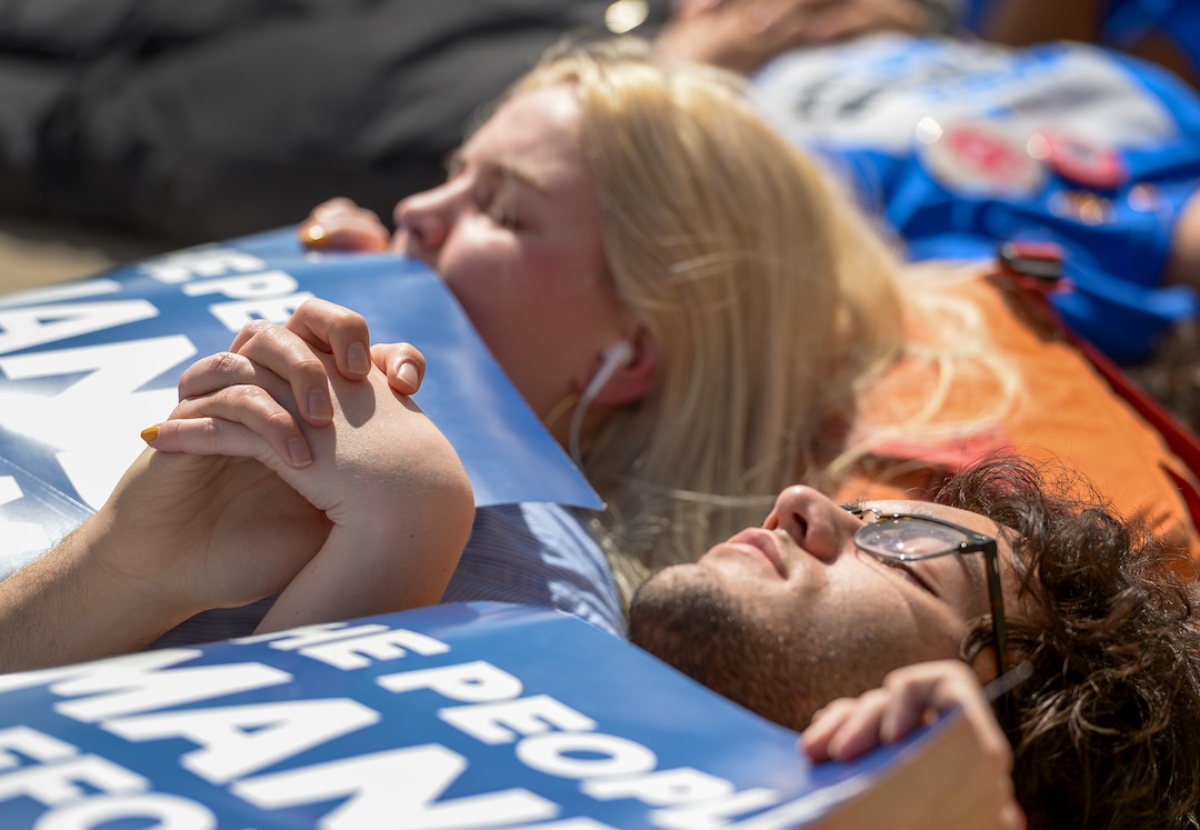 (Leah Hogsten  |  The Salt Lake Tribune)  Brighton High School students Lydia Barrett and Josh Carlucci hold hands as they participate in the 22-minute die-in for the 22 school shootings already in 2018. Members of March For Our Lives SLC members and concerned citizens gather at the Utah Capitol, Friday, May 18, 2018, to demand gun reform and honor the 10 dead who were killed during Friday morning's shooting spree inside Santa Fe High School in southeast Texas.