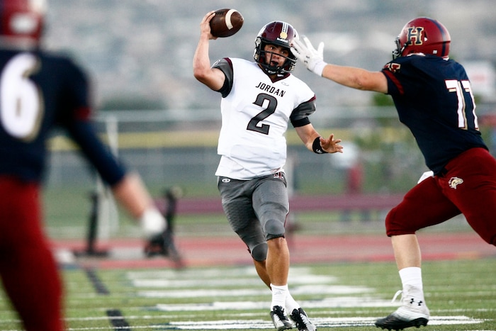(Chris Detrick  |  The Salt Lake Tribune)  Jordan's Austin Kafentzis (2) passes past Herriman's Nick Williams (77) during the game at Herriman High School Friday September 20, 2013.
