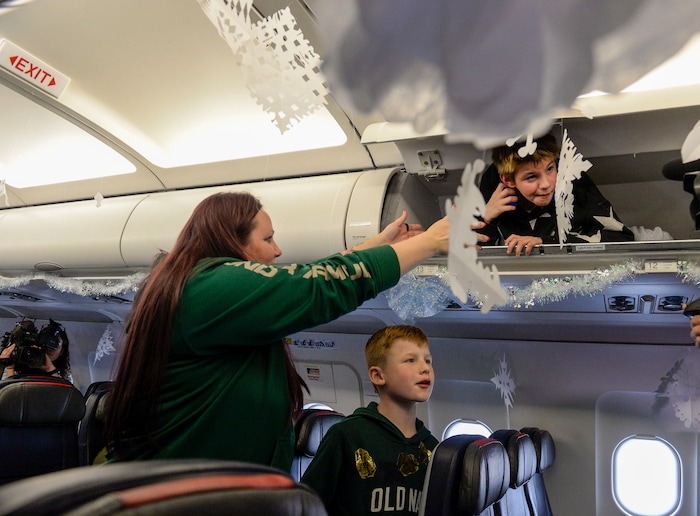 (Leah Hogsten | The Salt Lake Tribune) Tiffany Burgess of Seattle coaxes her son Zander, 11, out of the overhead bins as the Salt Lake City Gold Star families board the flight. Ten Gold Star families from Salt Lake City were treated to a Winter Wonderland scene, including Whoville and the Grinch at their boarding gate at Salt Lake International Airport, Dec. 7, 2019 before their flight to Disney World aboard the Snowball Express. This month, the Gary Sinise Foundation's Snowball Express will fly more than 1,700 family members of fallen U.S. military heroes to Disney World for a holiday retreat.