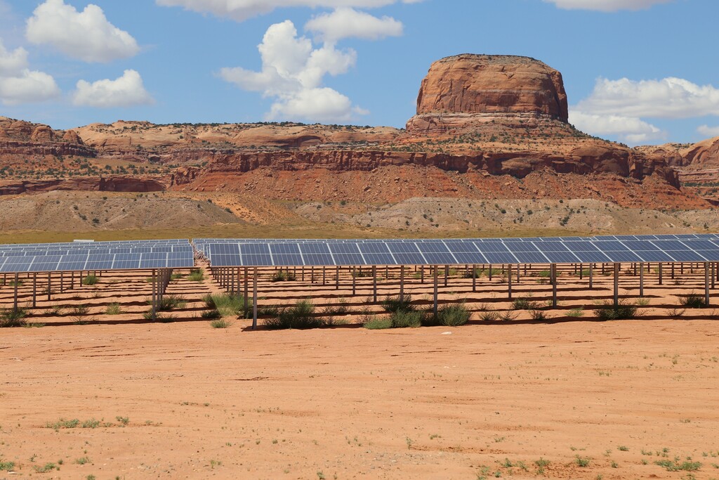 This Aug. 24, 2017 photo provided by Navajo Nation Office of the President and Vice President shows solar panels near famed sandstone buttes along the Arizona-Utah border on the Navajo Nation. The Kayenta Solar Facility is the first utility-scale solar project on the reservation, producing enough electricity to power about 13,000 Navajo homes. (Antonio Ramirez/Navajo Nation Office of the President and Vice President via AP)