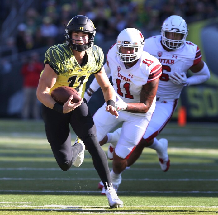 Oregon quarterback Braxton Burmeister, left, scrambles for yardage ahead of Utah's Kylie Fitts and Bradlee Anae during the first quarter of an NCAA college football game Saturday, Oct. 28, 2017, in Eugene, Ore. (AP Photo/Chris Pietsch)