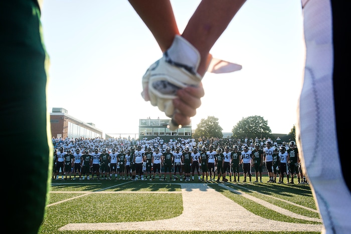 (Chris Detrick  |  The Salt Lake Tribune)    Members of the Hillcrest and Highland football teams hold hands during a remembrance for Hillcrest football coach Cazzie Brown before the game at Hillcrest High School Friday, September 1, 2017. Cazzie Brown passed away Sunday night after spending four days in the hospital. According to a family representative, Brown was brought to the emergency room Wednesday for complications with his thyroid. The doctors found that he had contracted meningitis, and later received a preliminary positive after being tested for West Nile virus. 