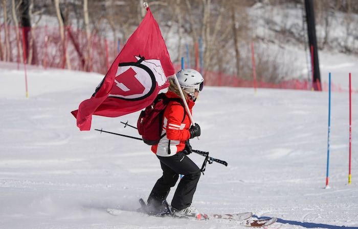 (Francisco Kjolseth | The Salt Lake Tribune) A University of Utah flag is carried down hill before the start of competition on Friday, March 11, 2022, as the slalom course is prepared for the NCAA Skiing Championships at Park City Mountain Resort. 