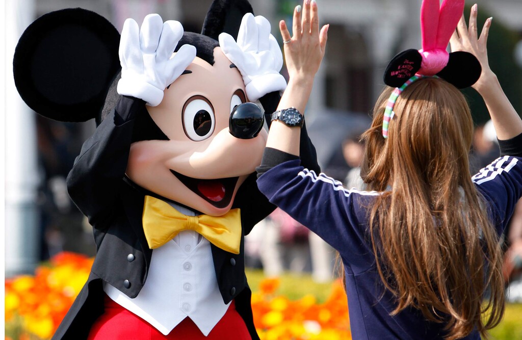 (Kiyoshi Ota | Bloomberg) Walt Disney's Mickey Mouse greets a visitor at Tokyo Disneyland in Urayasu city, Japan.