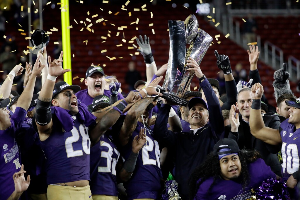 (AP Photo/Marcio Jose Sanchez) Washington coach Chris Petersen, shown hoisting the Pac-12 trophy after the 2016 championship game, said late-night kickoff times hurt the conference's national exposure.