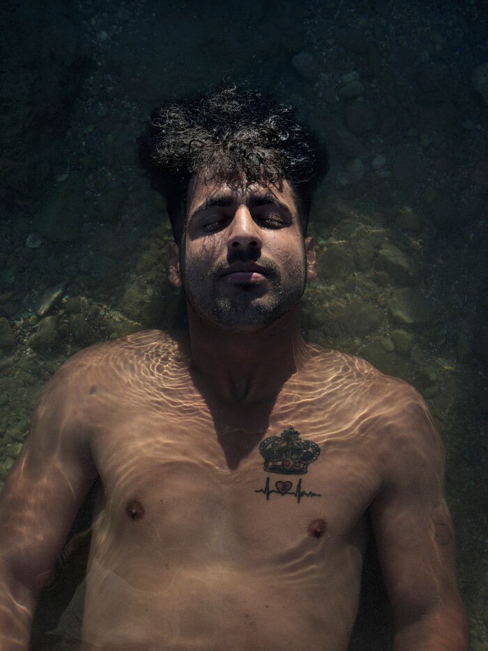 (Myrto Papadopoulos | The New York Times) Hasib Hotak, a homeless refugee from Afghanistan, cools down in the shallows of a beach in Athens, Greece, July 22, 2020. Around the world, the poor and marginalized are much more likely to be vulnerable to extreme heat; Hasib sleeps with other refugees on a rooftop that turns blazing hot by midday.