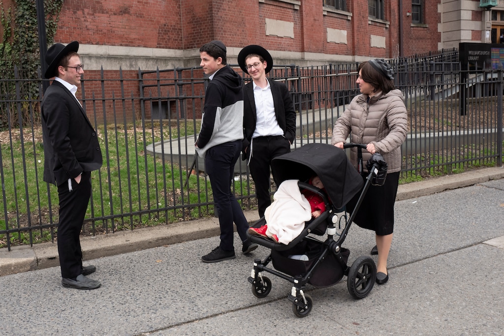 (AP Photo/Mark Lennihan) A woman, right, who identified herself as Ester, passes a group of boys, Tuesday, April 9, 2019, in the Williamsburg section of Brooklyn, New York. Ester says that she does not believe that the measles vaccination is safe. The city health department ordered all ultra-Orthodox Jewish schools in a neighborhood of Brooklyn on Monday to exclude unvaccinated students from classes during the current measles outbreak. In issuing the order, the health department said that any yeshiva in Williamsburg that does not comply will face fines and possible closure.