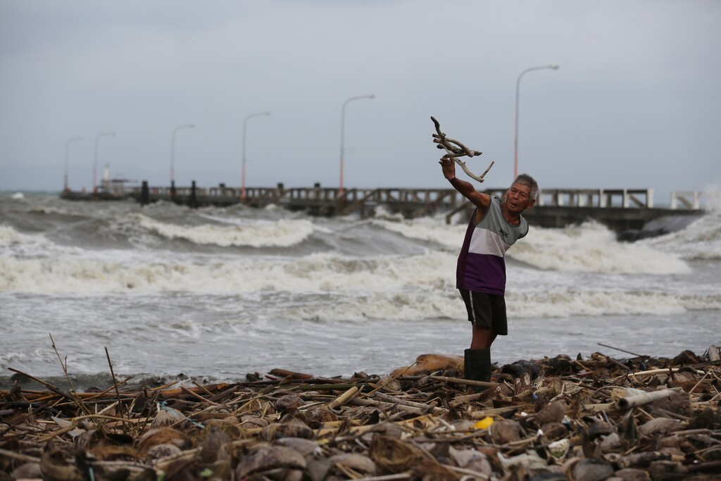 A man throws wood along the shore as strong waves brought Typhoon Hagupit hit Atimonan, Quezon province, eastern Philippines on Saturday, Dec. 6, 2014. Haunted by Typhoon Haiyan's massive devastation last year, more than 600,000 people fled Philippine villages and the military went on full alert Saturday to brace for a powerful storm only hours away from the country's eastern coast. (AP Photo/Aaron Favila)