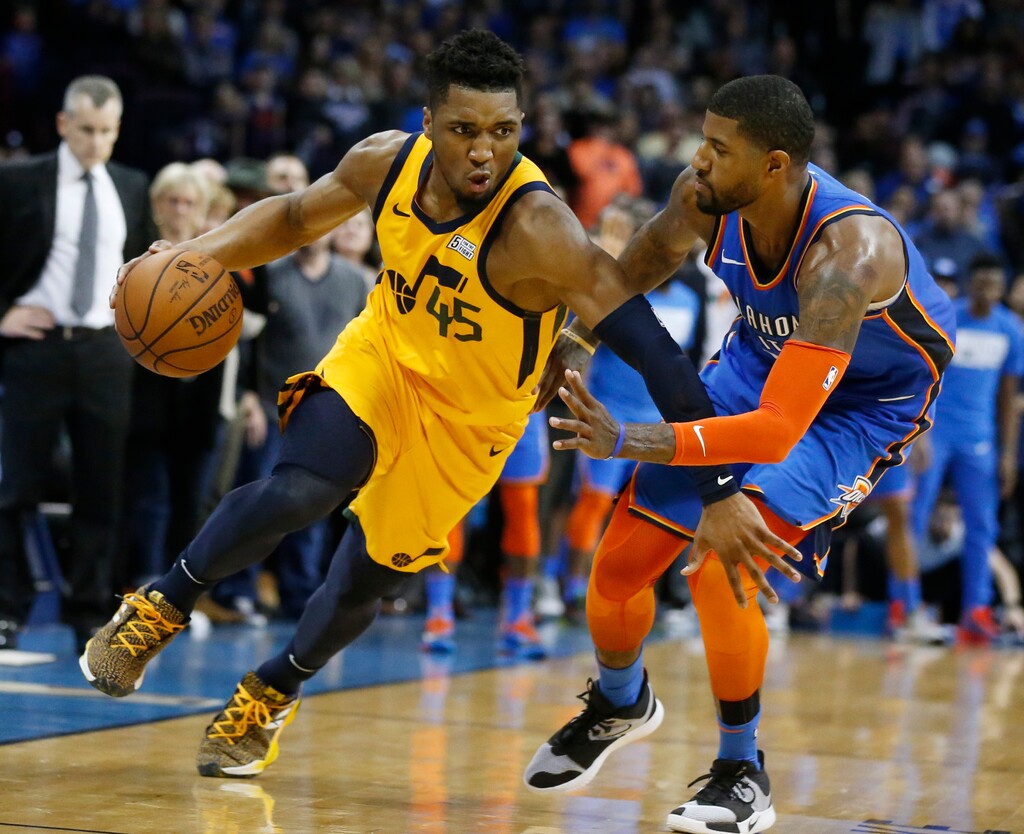 Utah Jazz guard Donovan Mitchell (45) drives around Oklahoma City Thunder forward Paul George during the second half of an NBA basketball game in Oklahoma City on Friday, Feb. 22, 2019. (AP Photo/Sue Ogrocki)