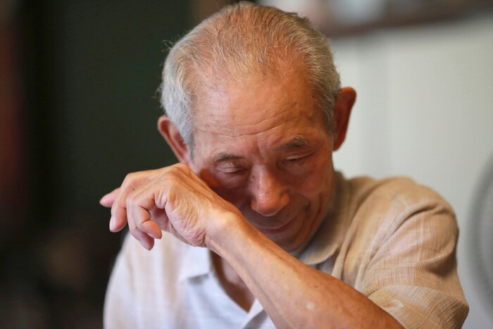 In this Aug. 14, 2017 photo, Tatsuya Yasue, 89-year-old farmer, wipes his tears while taking about his brother Sadao Yasue, who fell in battle during the war in Pacific more than 70 years ago, in Higashishirakawa, in central Japan's Gifu prefecture. Former U.S. Marine Marvin Strombo will returns Sadao's calligraphy-covered flag he took from the fallen Japanese soldier 73 years ago. (AP Photo/Eugene Hoshiko)