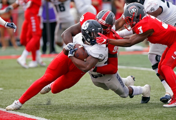 Utah State running back LaJuan Hunt, center, is tackled by New Mexico defensive lineman Kene Okonkwo (98) and cornerback D'Angelo Ross (3) 1 yard short of the end zone during the first half of an NCAA college football game in Albuquerque, N.M., Saturday, Nov. 4, 2017. Hunt scored a touchdown in the next down. (AP Photo/Andres Leighton)