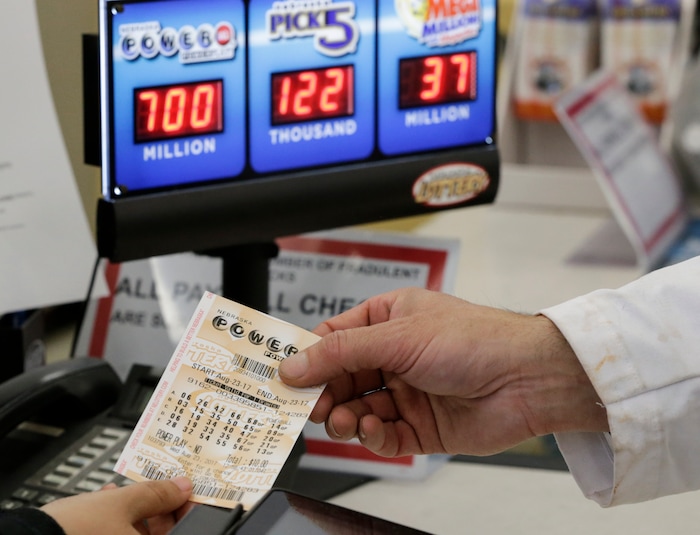 A customer is handed a Powerball ticket in Omaha, Neb., Wednesday, Aug. 23, 2017. Lottery officials said the grand prize for Wednesday night's drawing has reached $700 million. The second -largest on record for any U.S. lottery game. (AP Photo/Nati Harnik)