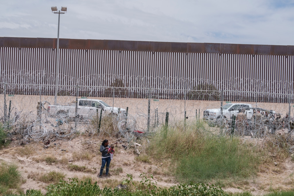 (Paul Ratje | The New York Times) A woman and holds her baby in front of a concertina wire fence on the U.S.-Mexico border in El Paso, Texas, seen from Ciudad Juarez, Mexico, on Tuesday, June 4, 2024. Officials with Mormon Women for Ethical Government are urging Americans to be more accepting and welcoming of asylum-seekers.