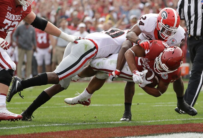 Oklahoma running back Rodney Anderson dives for a touchdown between Georgia defensive back J.R. Reed, left, and safety Dominick Sanders, right, during the first half of the Rose Bowl NCAA college football game, Monday, Jan. 1, 2018, in Pasadena, Calif. (AP Photo/Gregory Bull)