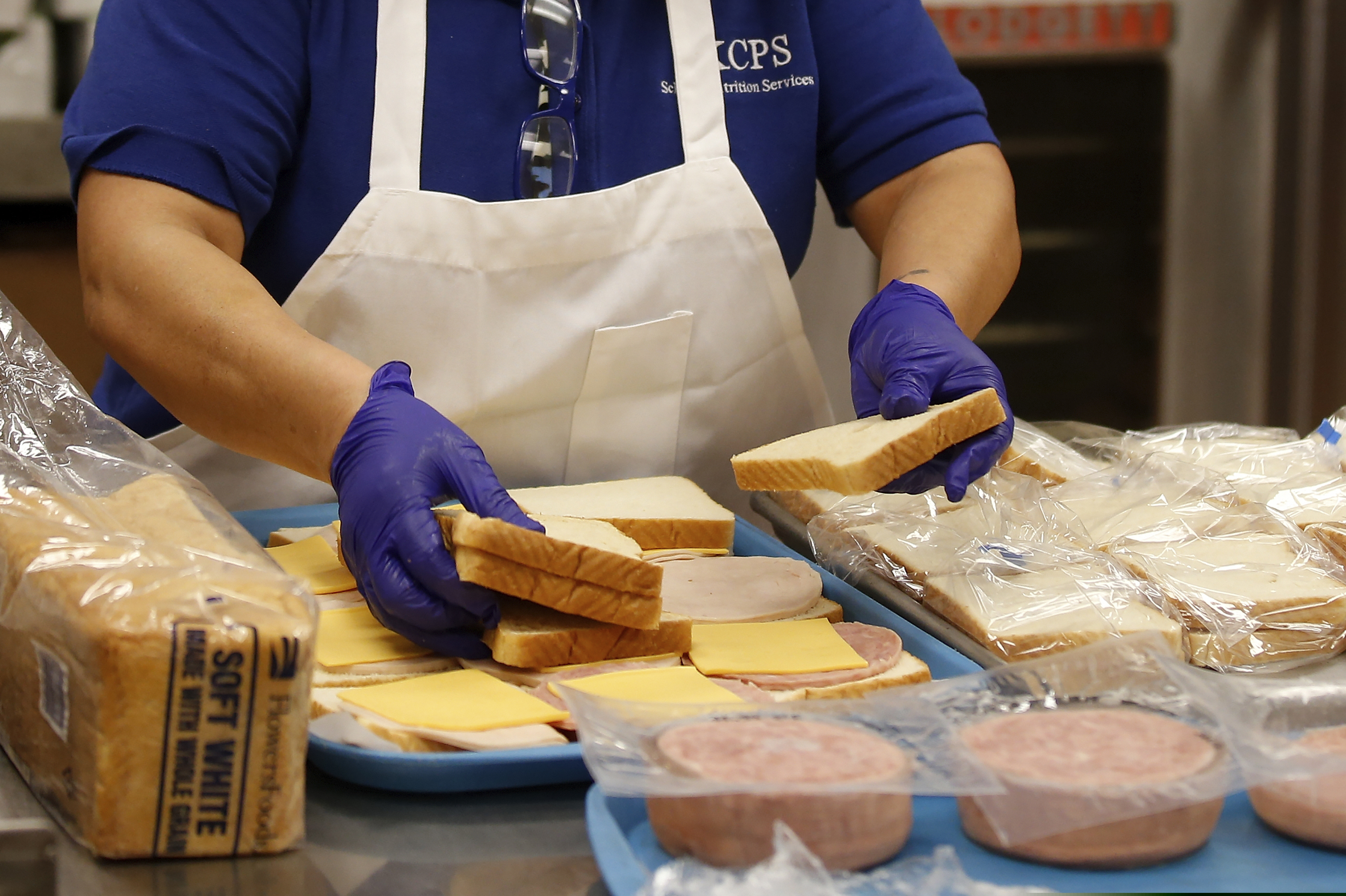 ADDS THAT ITS FIRST DAY OF FREE LUNCHED SINCE SCHOOLS WERE CLOSED - Kitchen assistant Maria Cedillo makes sandwiches for lunch bags at Rockwood Elementry School, as the city public school district holds their first day of providing free meals to students at 42 sites around the district during the coronavirus pandemic, in Oklahoma City Monday, March 24, 2020. Students get free lunches every day when school is in session, this is first day of free meals since schools were closed. (AP Photo/Sue Ogrocki)