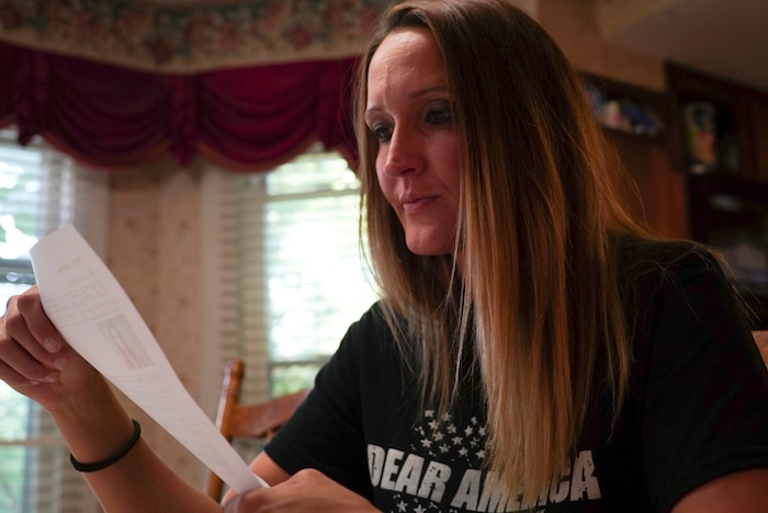 In this Aug. 9, 2017, photo,  Koriann Evans, a former drug addict, looks at her criminal history at her home in Bellevue, Ohio. Evans was hooked on heroin for over a decade until she overdosed while driving her car with her two children in the back, after which she stopped using drugs and started speaking about her former addiction. Police and rescue crews say drivers overdosing on heroin and other drugs are driving up the number of car crashes. (AP Photo/Dake Kang)