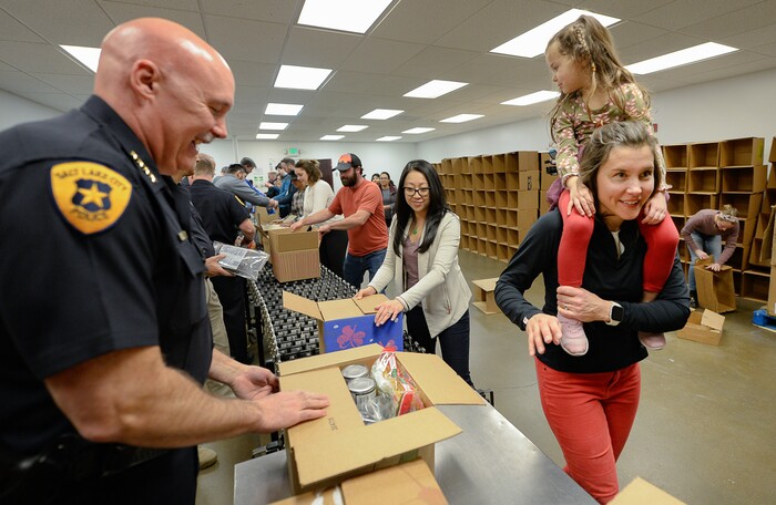 (Francisco Kjolseth  |  The Salt Lake Tribune) Police Chief Mike Brown closes up a box as Salt Lake City Mayor Erin Mendenhall works the line with daughter Mila LaMalfa, 4, in tow as they volunteer at the Utah Food Bank for the Martin Luther King Jr. Day of Service on Monday, Jan. 20, 2020.